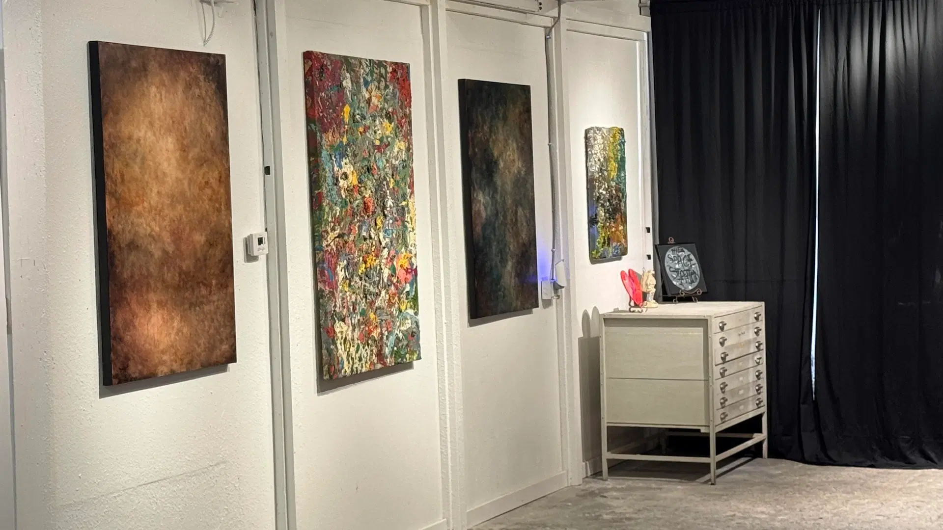 studio space with paintings on wall, white walls and white desk